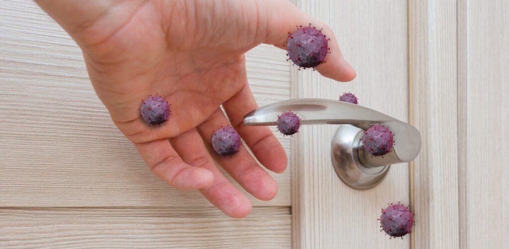 Hand touching doorknob with virus particles.